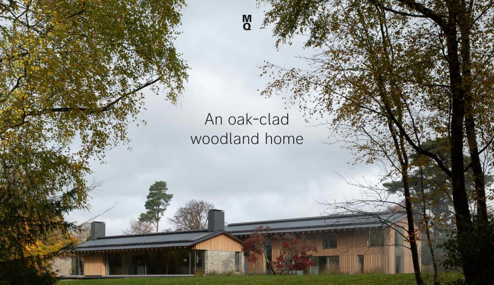 Photo of a two wood-clad buildings with a dark grey metal roof, beneath a dark grey skin. In the middle of the image, the words