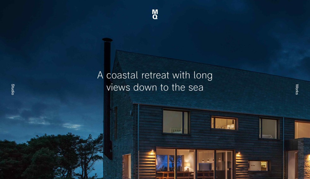 Image of a two storey building, designed in traditional coastal style. The photo is taken at night, and in the center of the image, the words