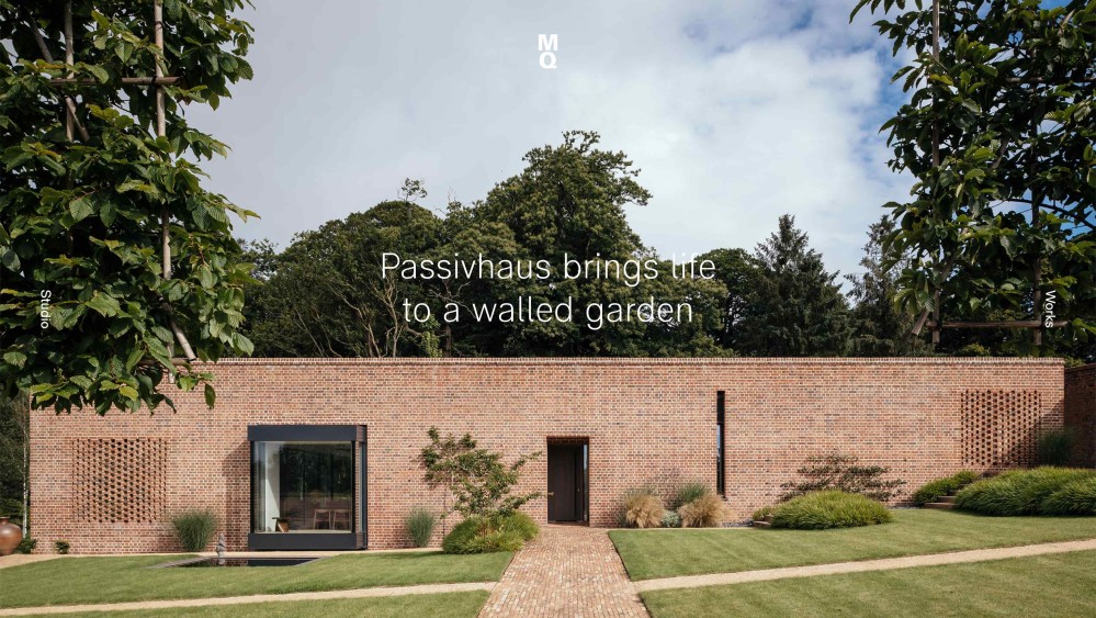 Photograph of a wide brown-brick building surrounded by lots of trees. At the top of the image is the words