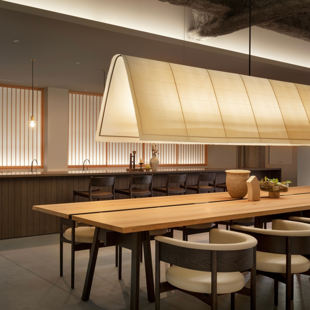 A large pendant hangs along the length of a dining table