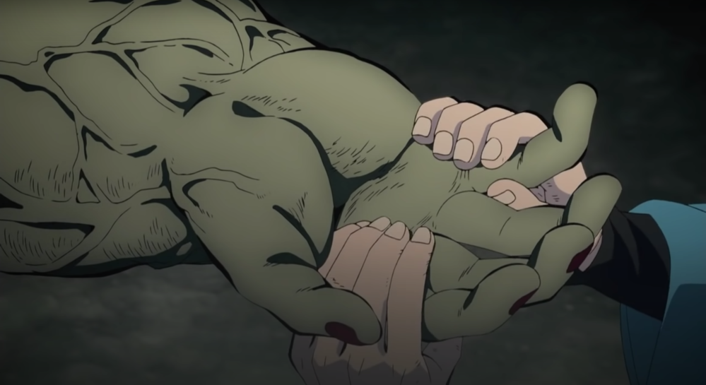 Screengrab of two human hands cradling a monstrously large green hand connected to a heavily veined arm. It’s heavily implied that this is the hand and arm of a very large green monster of some kind.