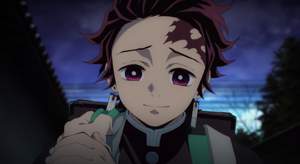 Screengrab of Tanjiro looking kindly down while gently touching a hand that has grabbed his cloak.