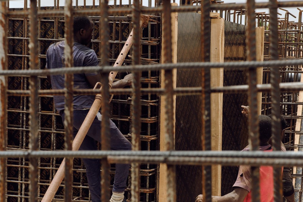 Two men working within a lattice of iron rods