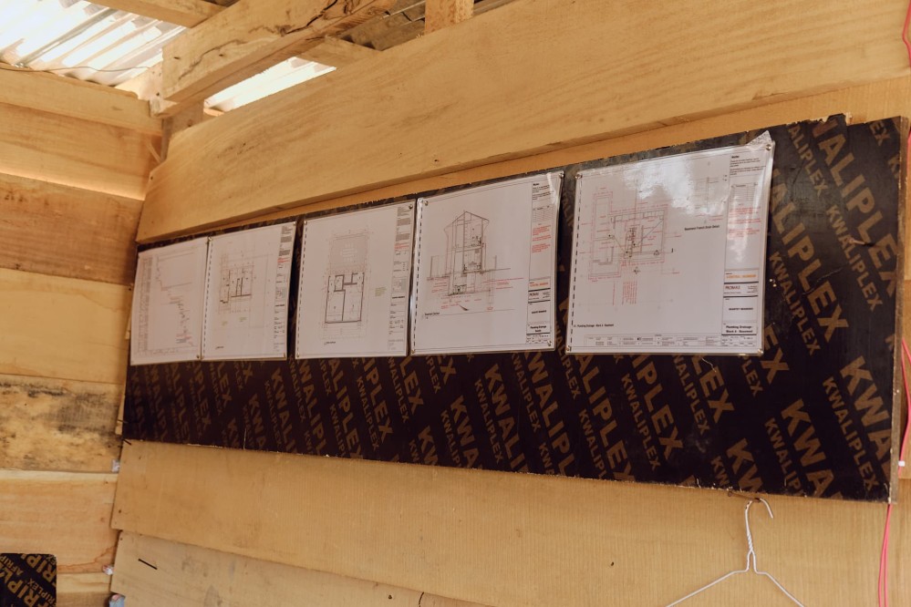 View from inside the temporary site office. On the wood plank walls you can see the floor plans of the building under construction