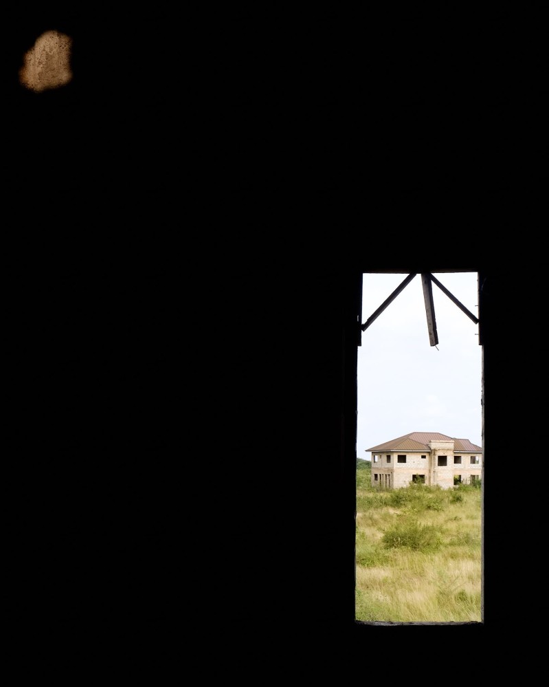 A house under construction in the distance, framed by window