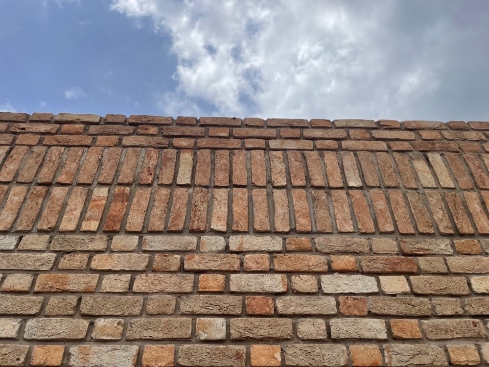 Close-up of the roofline of a brick building against a bright blue sky