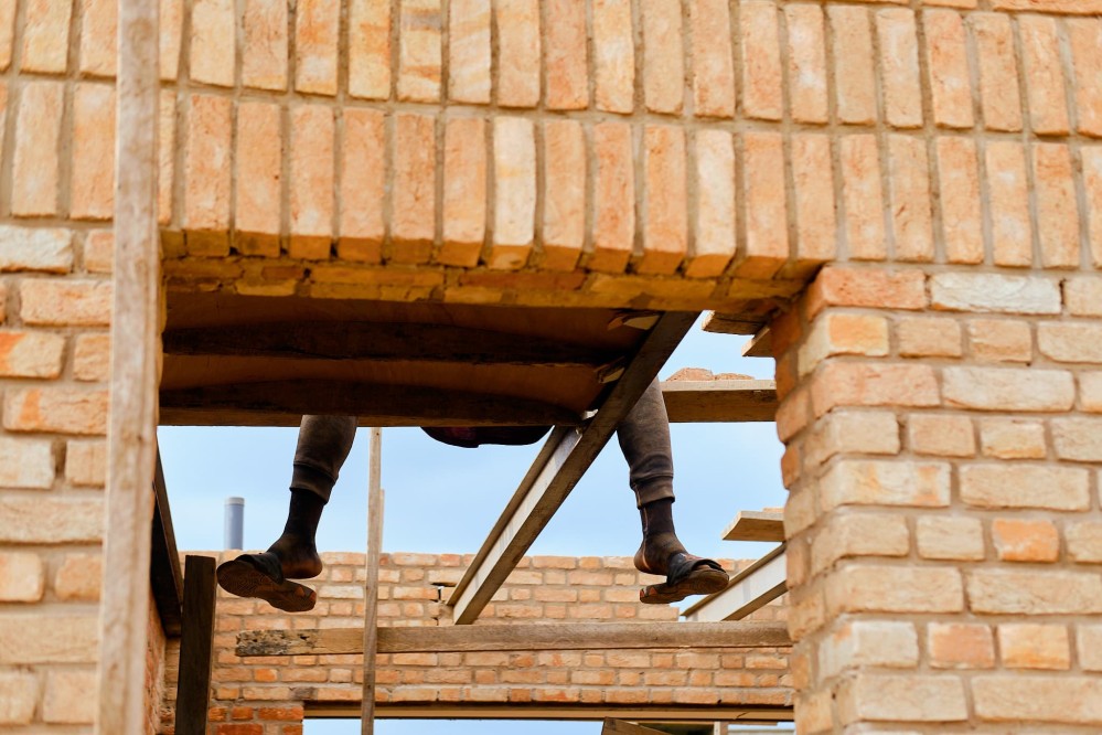 A worker's dangling legs seen through a brick doorway