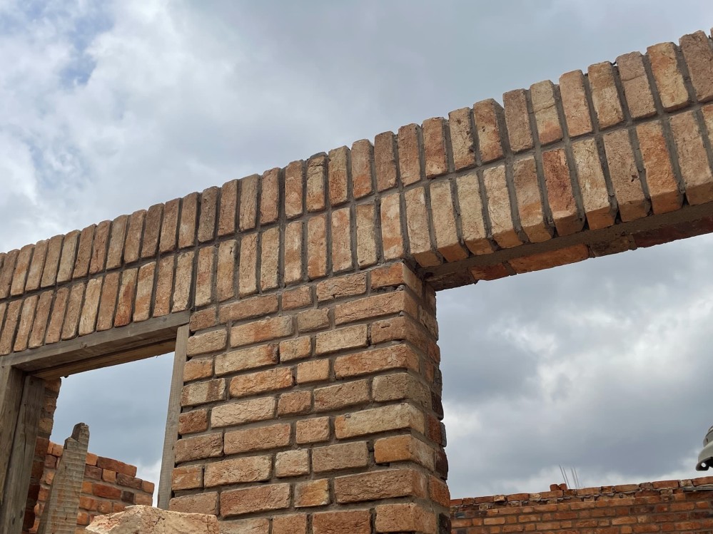 Brick wall without a ceiling. You can see the sky through holes meant for windows.