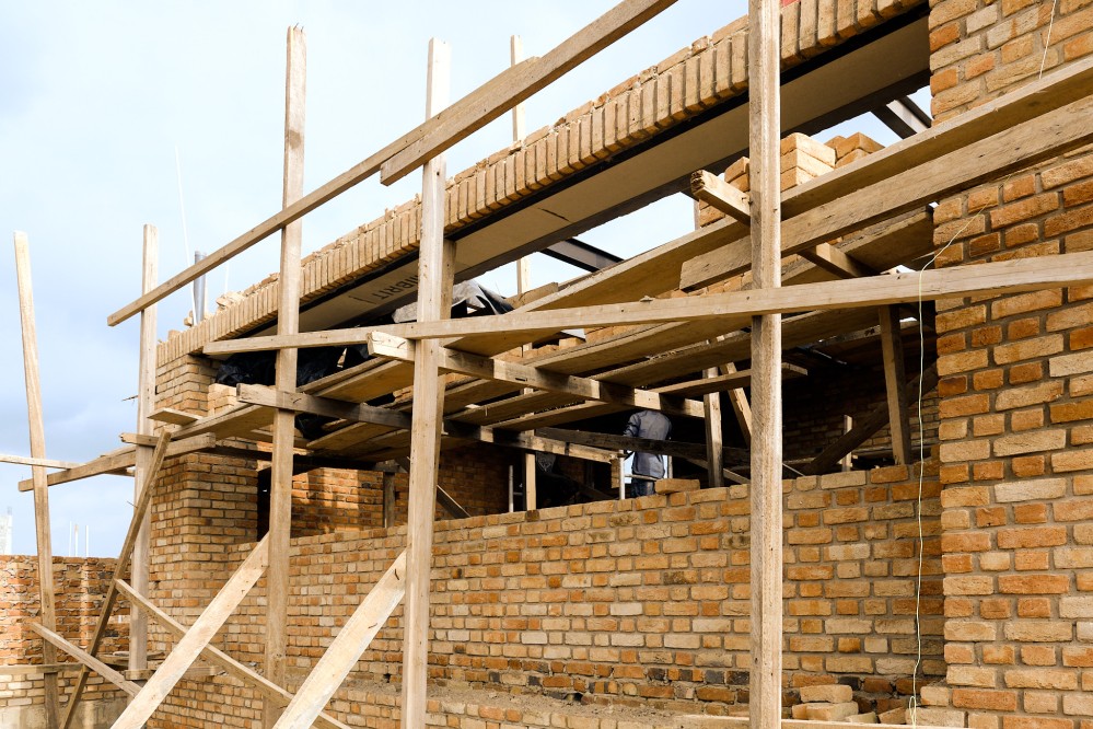 Front facade of a single storey brick building under construction. It has a generously wide window.