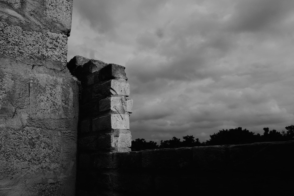 Moody black and white shot of a half-completed brick wall meeting an unfinished concrete wall