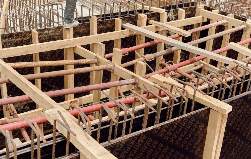 Several pipe criss-cross between wooden formwork in the basement