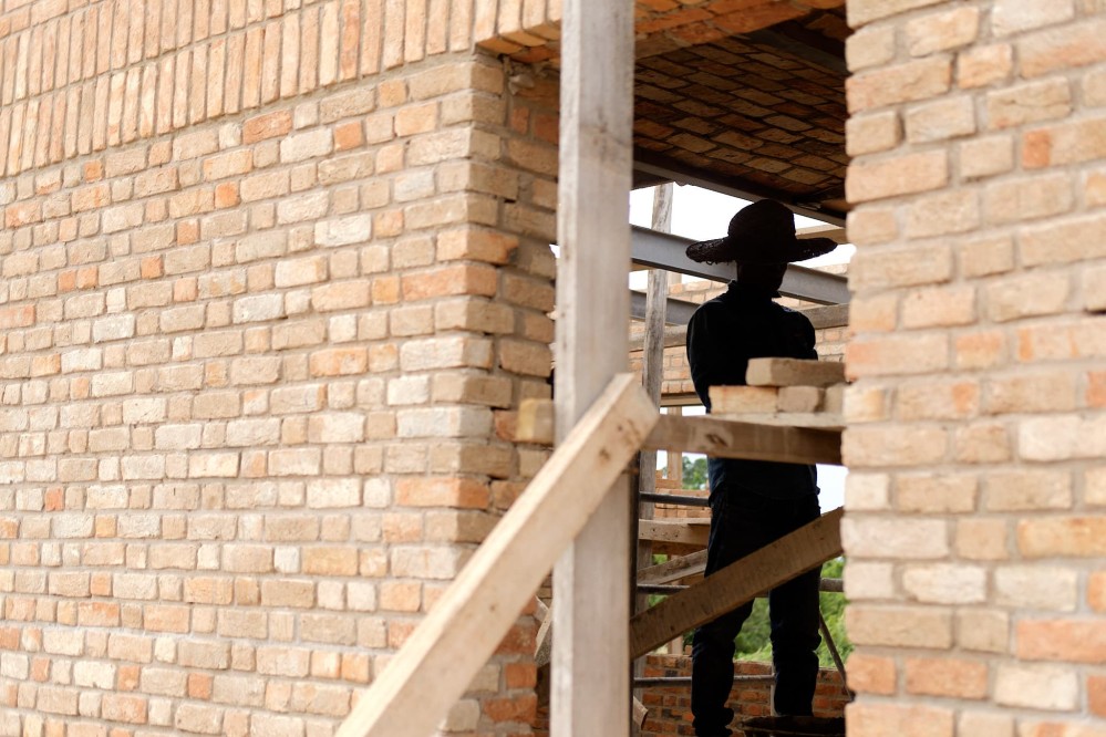 A worker in a large brimmed hat outlined in a brick doorway