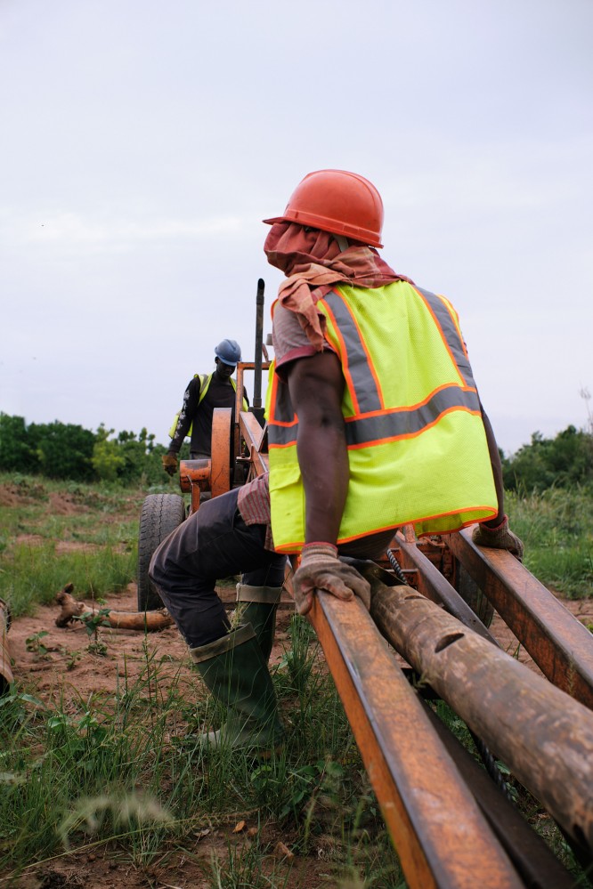 A man in a helmet and bright reflective vest takes a brief break