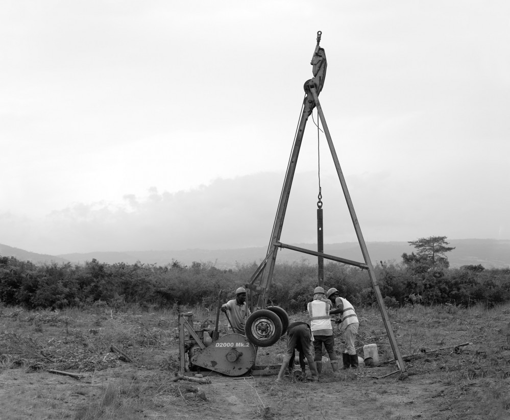 Black and white photo of four mean operating a drilling device